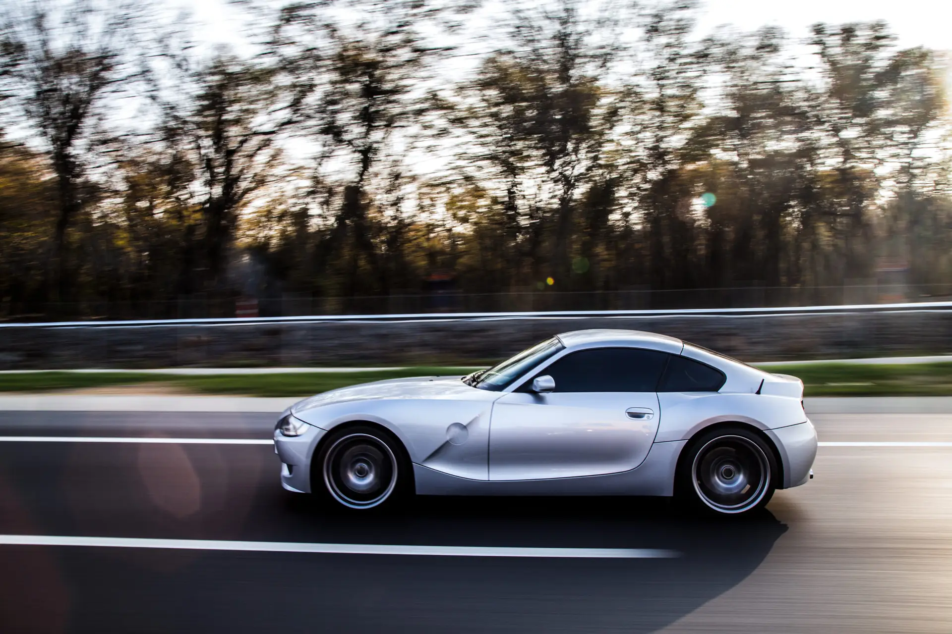 silver-metallic-color-coupe-driving-by-forest